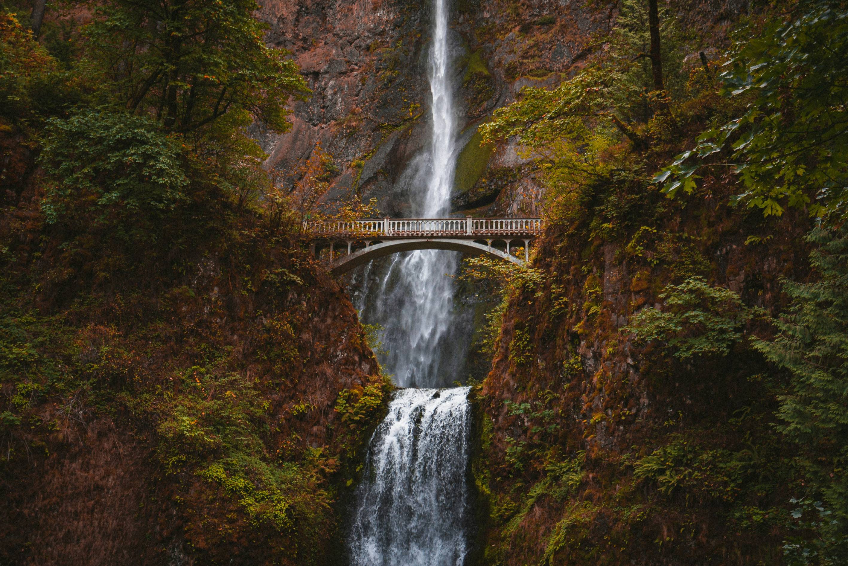 white bridge over waterfalls during daytime