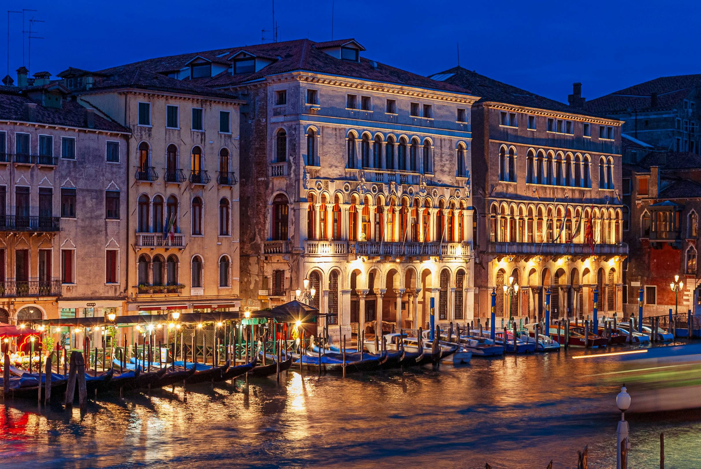 Buildings illuminated over a canal in venice at night.