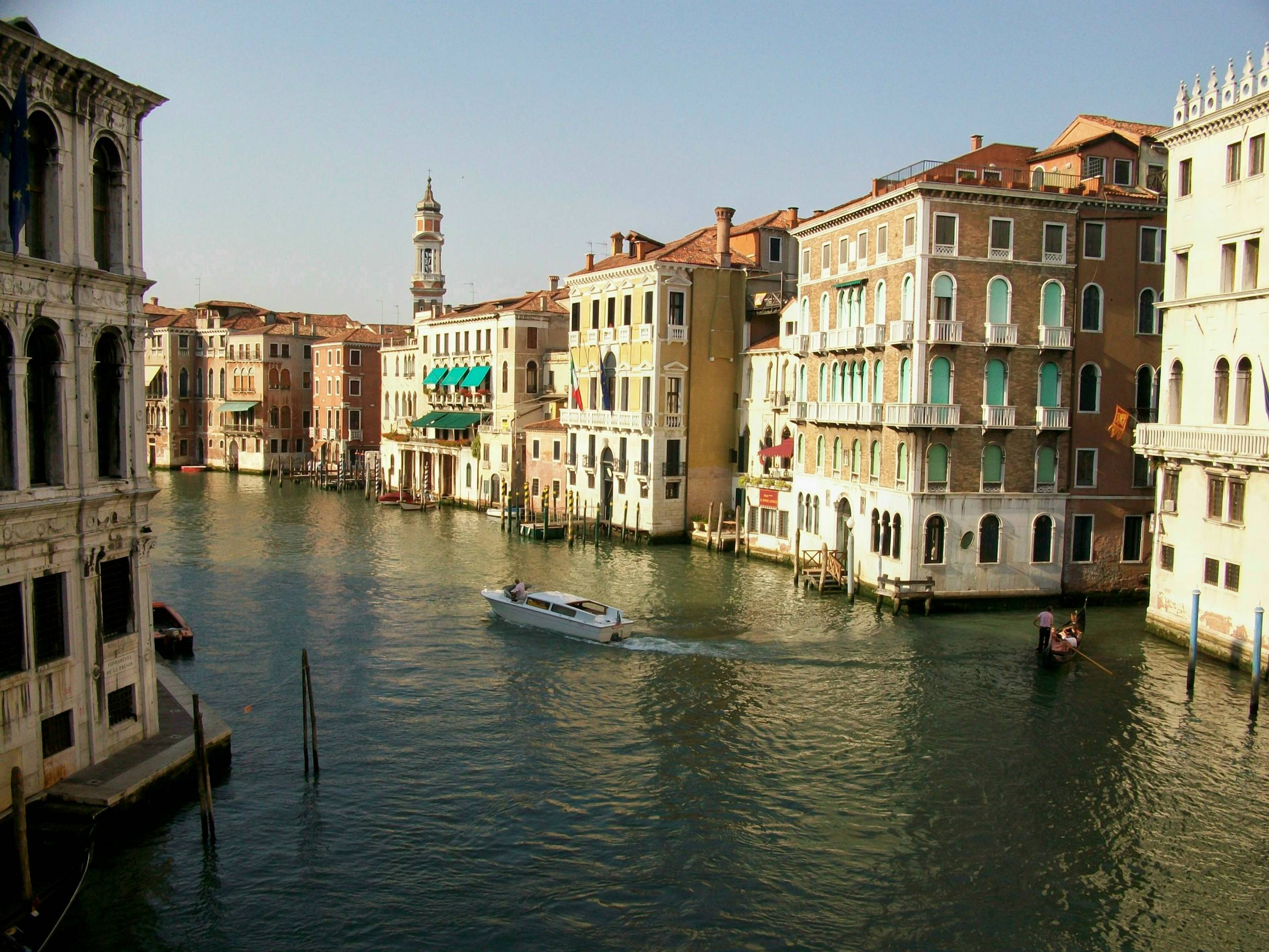 people riding on boat on river between buildings during daytime