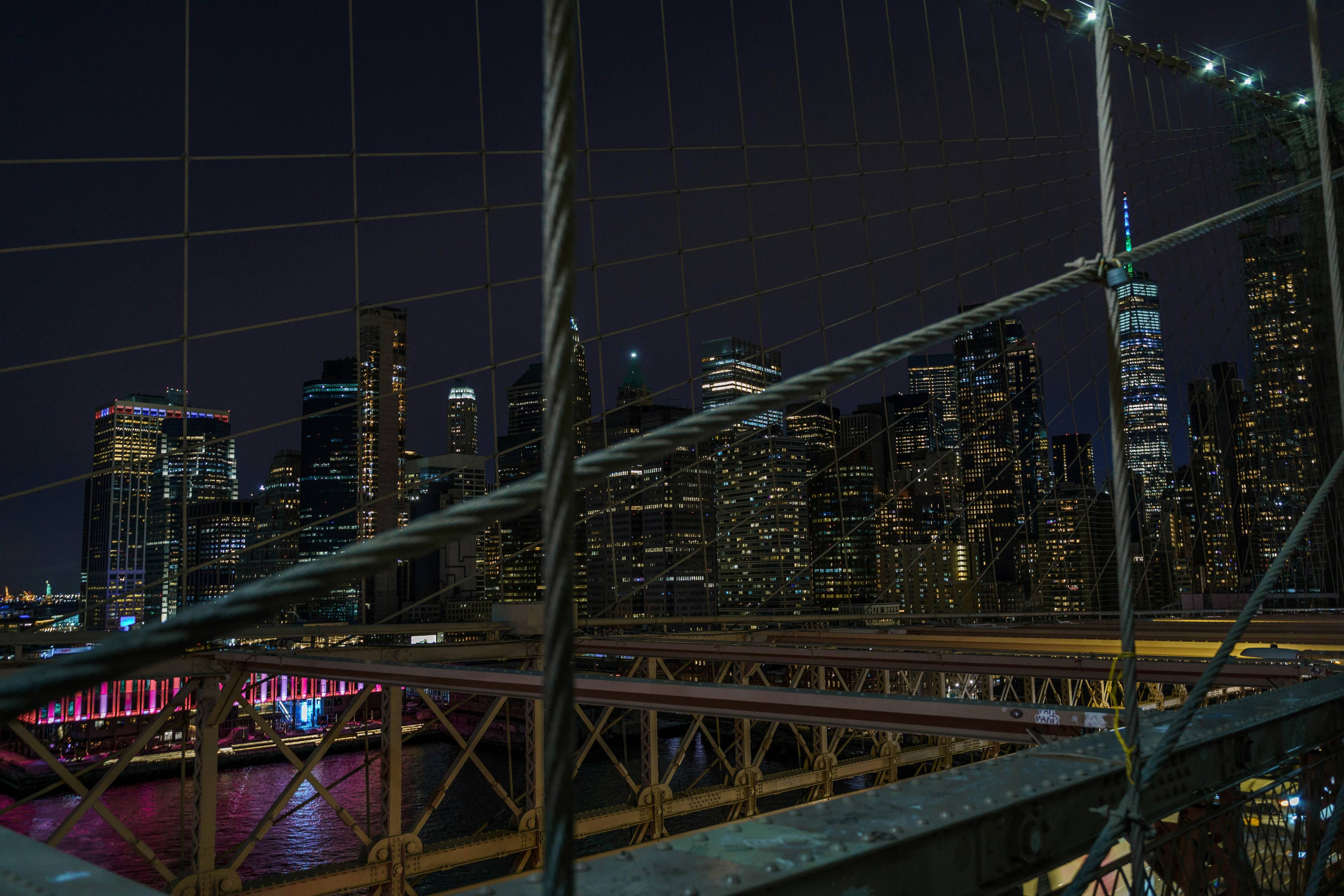 red and yellow bridge near city buildings during night time